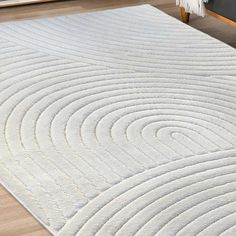 a large white rug with wavy lines on the floor in front of a wooden table