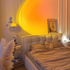 a white bed sitting in a bedroom next to a yellow sun painting on the wall