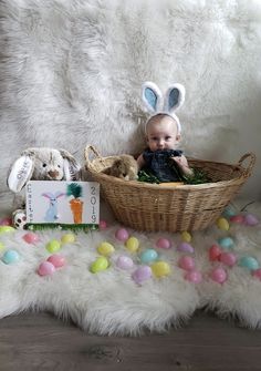 a baby sitting in a basket with easter decorations