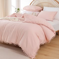 a bed with pink sheets and pillows on it