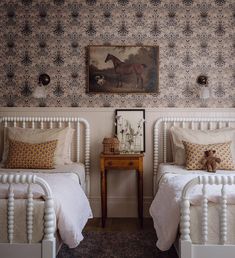 two white twin beds in a bedroom with wallpaper