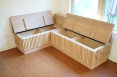 an empty wooden bench sitting on top of a hard wood floor next to a window