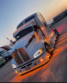 a white semi truck with lights on it's front bumper is parked in a parking lot