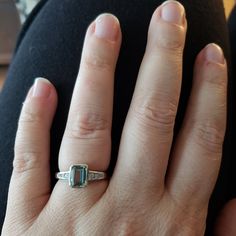 a woman's hand with a ring on it and an emerald stone in the middle