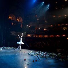 two ballerinas are performing on stage in front of an audience