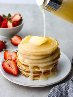 a stack of pancakes with syrup being poured on top