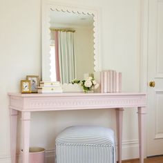 a pink dressing table with a mirror and stool