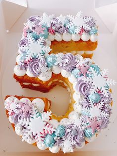 a cake shaped like the number five with frosting on it's edges and snowflakes