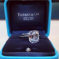 an engagement ring in a blue box with the words tiffany & co on it's side