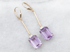 These elegant and luminous earrings feature yellow gold and amethyst set with a diamond accent, making it perfect for making a statement. Amethyst is known for its strength and protection properties, while the diamond accents provide the perfect touch of glam.Metal: 14K Yellow GoldGem: 2 Amethyst totaling 12.25 CaratsGem Measurements: 10.1 x 13.8 mm, Emerald CutAccents: 2 Diamonds totaling .10 Carats, SI in Clarity, G in ColorMeasurements: 10.1 x 54.3 mmMarks: "14KS" Stamped on the findings Amethyst Earrings Fine Jewelry For Formal Occasions, Amethyst Gemstone Earrings For Formal Occasions, Formal Amethyst Gemstone Earrings, Elegant Amethyst Earrings For Formal Occasions, Purple Fine Jewelry Earrings For Formal Occasions, Formal Amethyst Drop Earrings, Formal Purple Diamond Earrings, Elegant Purple Earrings With Prong Setting, Elegant Purple 14k Gold Earrings