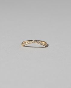 a yellow gold wedding band with small diamonds on the side, set against a plain grey background