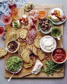 a wooden tray topped with different types of food and dips on top of it