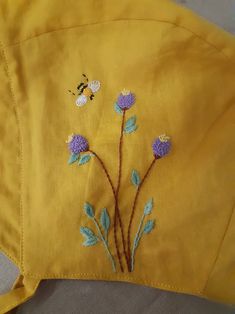 a yellow jacket with blue flowers and a bee on the back, embroidered onto it