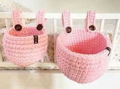 two pink crocheted baskets sitting on top of a wooden floor next to a bed