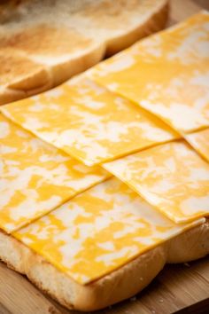 slices of bread with cheese on them sitting on a cutting board