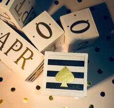 several wooden blocks with gold foiled letters and playing cards on them, sitting next to each other