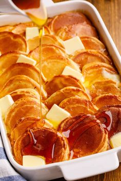 a casserole dish is being drizzled with honey and butter on a wooden table