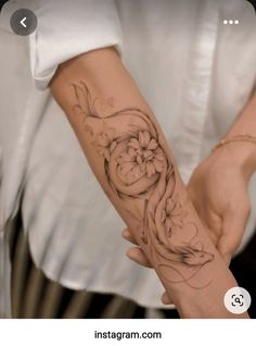 a person with a tattoo on their arm holding onto a hand that has a flower in it