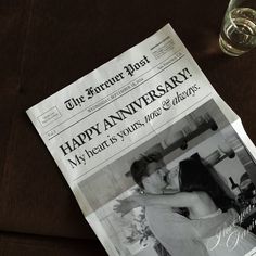 a newspaper with a photo of a man and woman kissing on it next to a glass of water