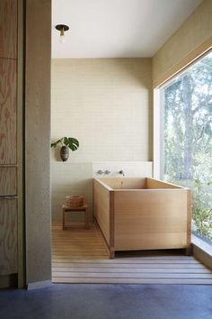 a large wooden bathtub sitting next to a window in a room with wood flooring