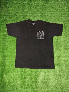 a black t - shirt with the word detroit on it sitting on a green carpet