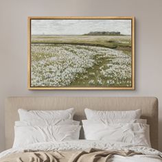 a painting hanging above a bed with white sheets and pillows on it's headboard