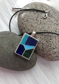 This mosaic necklace pendant features hand-cut blue and green stained glass. Silver grout was used to bring out the colors. Grout sealant was used to protect this work of art. The pendant features a rectangular silver bezel tray measuring 1 x 1.25 (25 x 30mm). Pendant is suspended on a black waxed Silver Grout, Stained Glass Necklace, Mosaic Jewelry, Metalsmithing Jewelry, Micro Mosaic, Unusual Design, Grout, Glass Necklace, Flower Jewellery