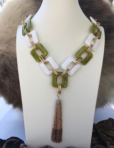 "Bring that beach vibe with you where ever you go with this lively lime green-white chunky acrylic necklace. Chunky acrylics are the trend for 2022 and this will fit perfectly to that retro-trendy look. Hanging tassel with pave top and beads in ombre color make the necklace extra special. .The gold plated oval aluminum links really pop and add interest to this already fabulous piece. Such a statement necklace with its big and bold vibe, you will really love adding it to your wardrobe . This necklace can easily go from lunch to dinner, dress up or down and look fabulous on your next Zoom Call. This necklace has no bounds:) Details: Acrylic Links Gold plated aluminum links Plated metals Carabiner Closure  Pave Crystal Tassel Top-4\" with crystal seed ombre beads Apprx. Measurements: 20\" Dro Military Messenger Bag, Acrylic Necklace, Acrylic Necklaces, Necklace Chunky, Zoom Call, Ombre Color, Jewelry Outfit, Beaded Tassels, Beach Vibe