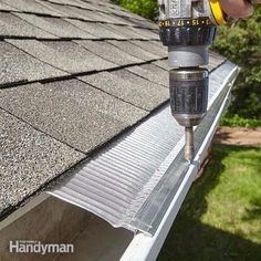 a person using a drill to fix a gutter vent on a house's roof