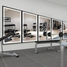 an empty gym room with mirrors and exercise equipment on the wall, along with two rows of treadmills