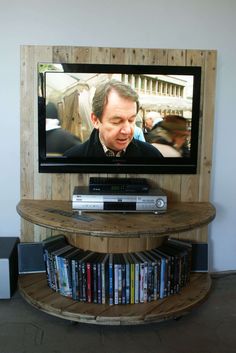 a tv that is on top of a wooden stand with dvd's in front of it