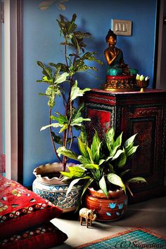 a buddha statue sitting on top of a wooden cabinet next to a potted plant