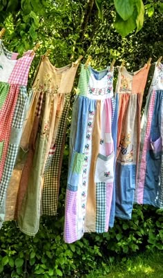 clothes hanging on a line in front of some green bushes and trees, with leaves around them