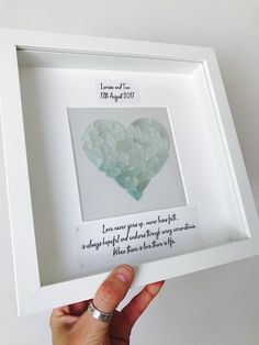 a person holding up a white frame with a heart shaped piece in it's center