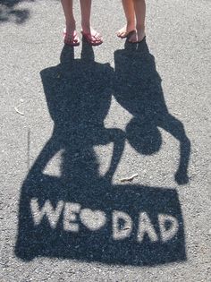 two people standing on top of a sign that says wed dad with the shadow of a motorcycle