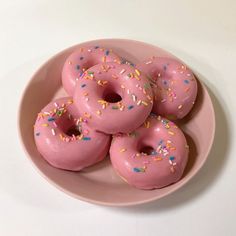 a pink plate filled with donuts covered in sprinkles