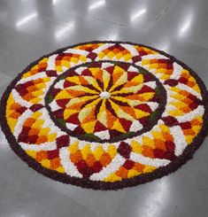 a circular rug with an orange, yellow and red flower design on it's surface