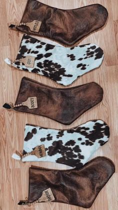 three pairs of cow print oven mitts sitting on top of a wooden floor next to each other