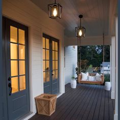 a porch with two doors and some lights on the side of it that are hanging from the ceiling