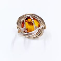 The listing is for a Vintage Silver Amber Ring. The ring features a round amber cabochon high bezel set on the rings frame with a organic silver design around the set amber. The setting of the ring allows you to see the natural inclusions of the amber when light passes through it. Weight: 12 grams Size: 6 Measurements: 1.0295 inches long and 1.1650 inches wide Marked: 4 hallmarks: one stamp for G 925 (silver content) with a of a lady in right profile and a second lady stamp on the outside of the Modern Amber Rings For Anniversary, Modern Amber Oval Ring, Modern Amber Gemstone Ring, Amber Sterling Silver Oval Cabochon Ring, Amber Oval Cabochon Sterling Silver Ring, Adjustable Amber Cabochon Rings, Amber Sterling Silver Ring With Oval Cabochon, Modern Handmade Amber Rings, Handmade Modern Amber Rings