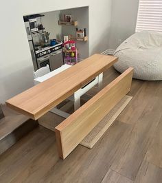 a wooden table sitting on top of a hard wood floor next to a white bed