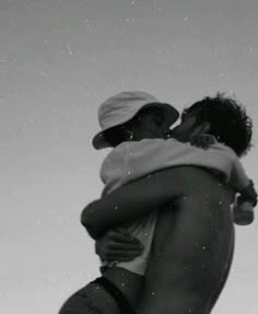 black and white photograph of two men embracing each other in front of a sky background