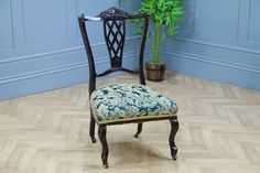 a chair sitting on top of a hard wood floor next to a potted plant