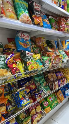 an assortment of snacks on shelves in a grocery store, including chips and cereals