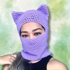 a woman wearing a purple knitted cat mask