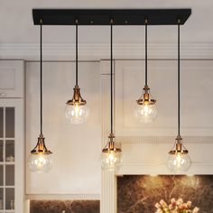 three lights hanging from the ceiling above a kitchen table with flowers in vases on it