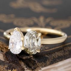 two yellow and white diamond engagement rings on top of a book with gold trimming