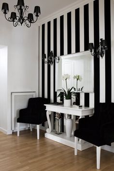 a black and white striped wall in a room with two chairs, a table and a chandelier