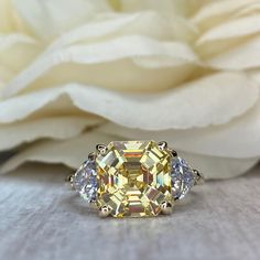 a yellow diamond ring sitting on top of a white flower