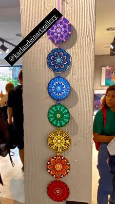 a woman standing next to a wall hanging with colorful circles on it's side